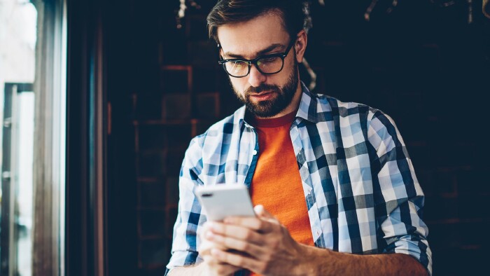 Junger Mann blickt auf sein Smartphone