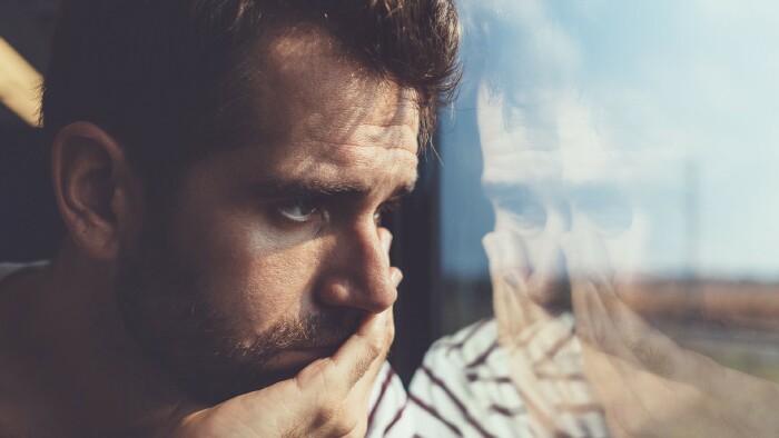 Junger Mann blickt traurig aus dem Fenster