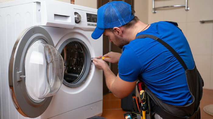 Ein Installateur repariert eine Waschmaschine.