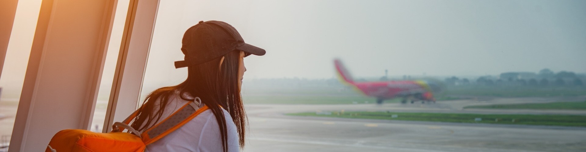 Reisende blickt am Flughafen aus dem Fenster in Richtung Flugzeug