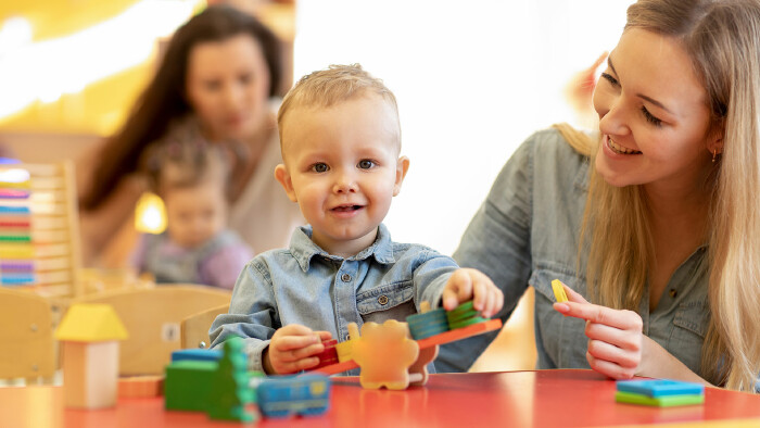 Kinderg&auml;rtnerin spielt mit Kleinkind im Kindergarten