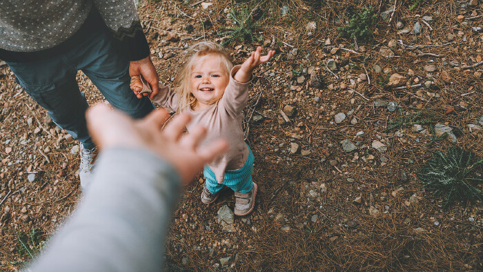 © Everst, stock.adobe.com Ein kleines Mädchen geht mit Vater und Mutter im Freien spazieren.
