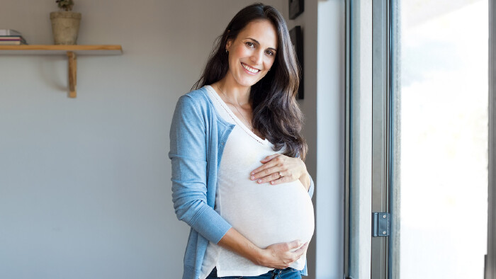 Eine gl&uuml;ckliche, schwangere Frau mit braunen Haaren
