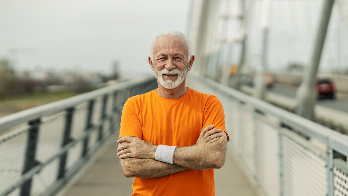 Älterer Mann posiert auf einer Brücke