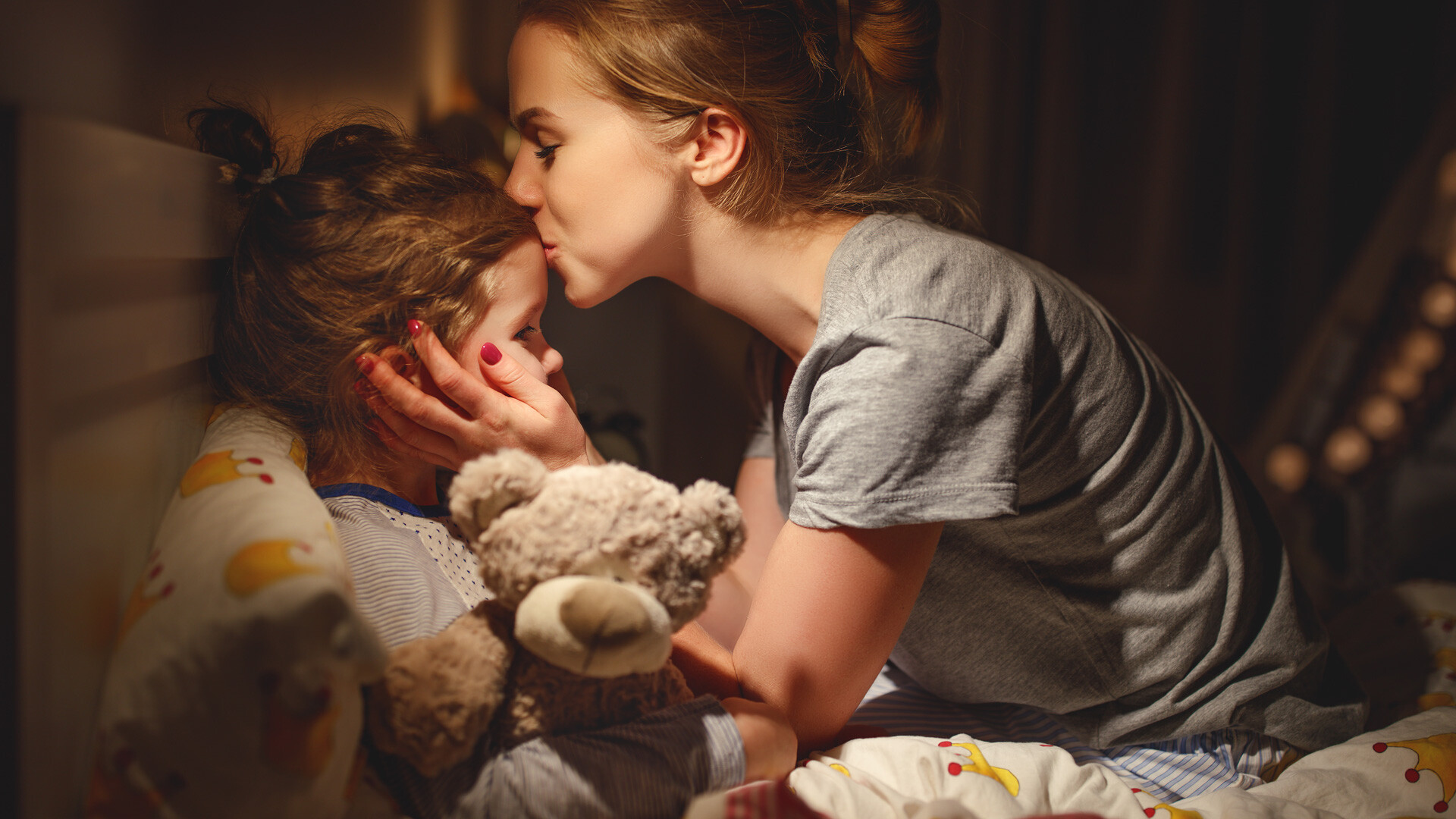 Mutter bringt krankes Kind zu Bett