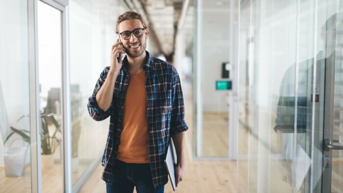 Junger Mann mit Laptop, der während der Arbeit telefoniert