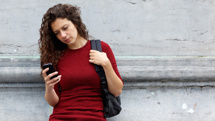 Junge Frau schaut mit ernstem Gesichtsausdruck auf ihr Smartphone