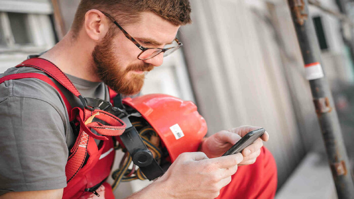 Bauarbeiter auf einem Gerüst mit Handy