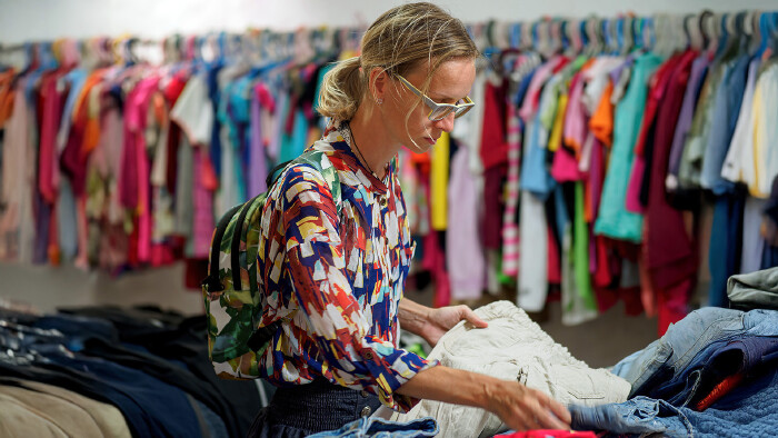 © Andrei, stock.adobe.com Frau sucht Second-Hand-Kleidung im Kleidergeschäft aus
