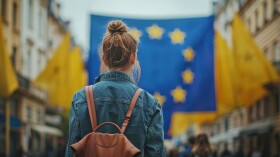 Junge Frau steht vor einer Europa Flagge