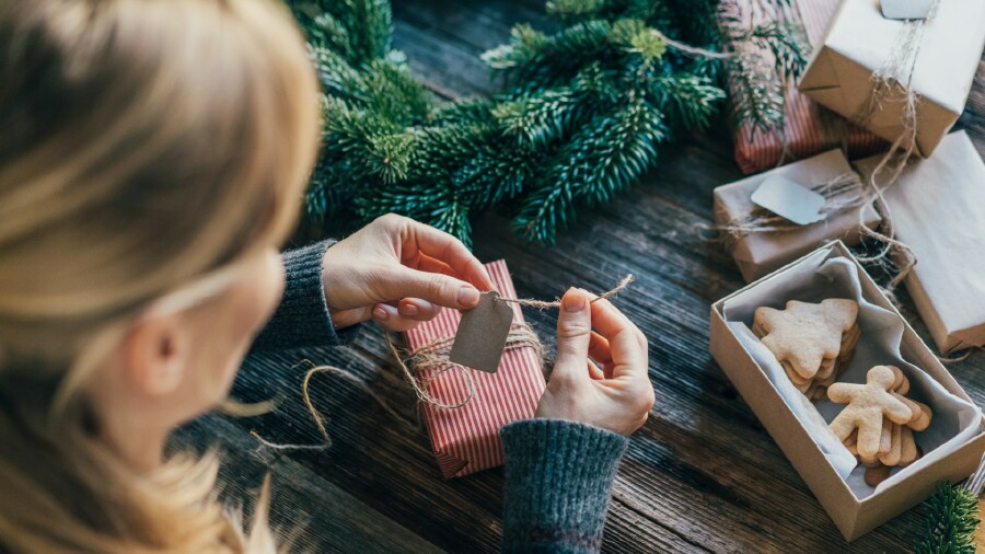 © Titova Ilona, stock.adobe.com Junge Frau packt Geschenke für Weihnachten ein.
