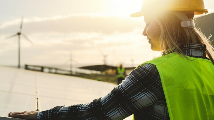 Junge Ingenieurin im Einsatz für alternative Energien mit Windrad und Solarpanel 