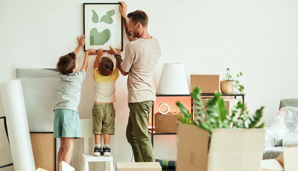 Papa und Söhne hängen ein Bild in der neuen Wohnung auf