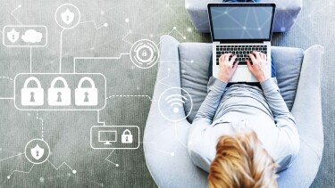 Mann sitzt mit seinem Laptop in einem modernen grauen Stuhl.