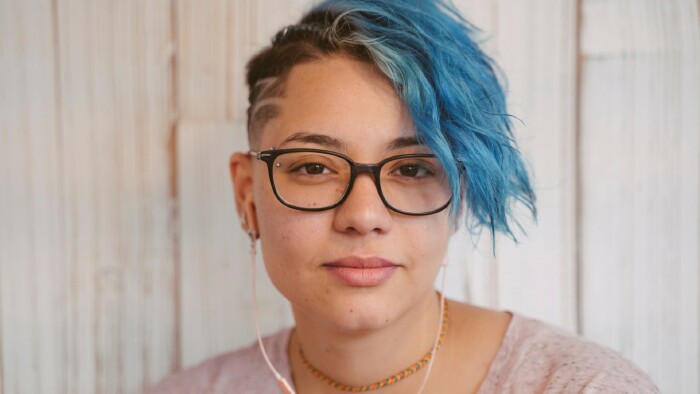 Junge Frau mit blau gefärbten Haaren schaut in Richtung Kamera