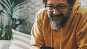 Nahaufnahme eines freundlichen Herrn, der auf sein Handy schaut