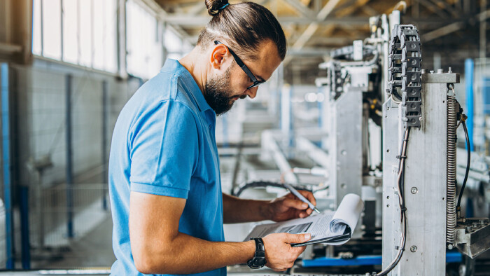 Arbeiter mit Klemmbrett in Produktionshalle