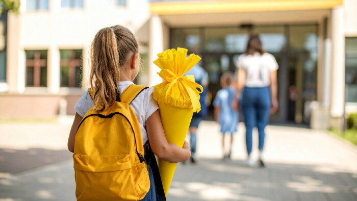  Kind mit gelber Schult&uuml;te auf dem Schulhof