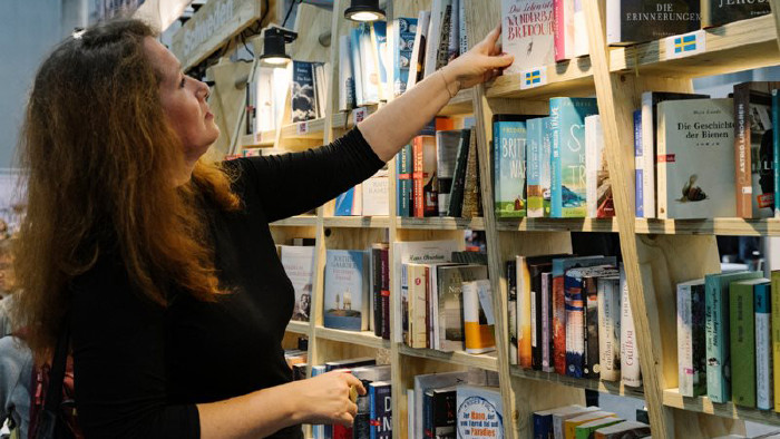 © Buch Wien Junge Frau nimmt ein Buch aus dem Regal © Buch Wien