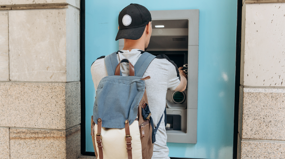 Junger Mann hebt bei Bankomat Geld ab