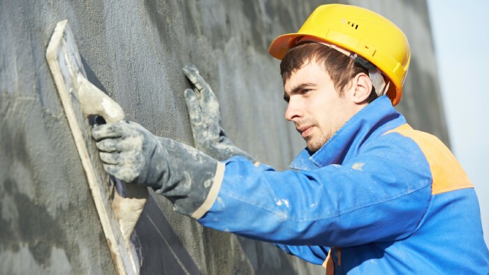 © Kadmy, stock.adobe.com Bauarbeiter bei Verputzarbeiten an der Fassade