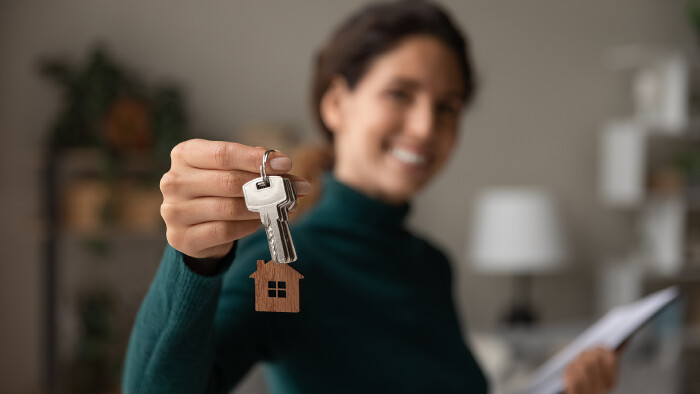 Junge Frau erhält die Schlüssel zu ihrer neuen Wohnung