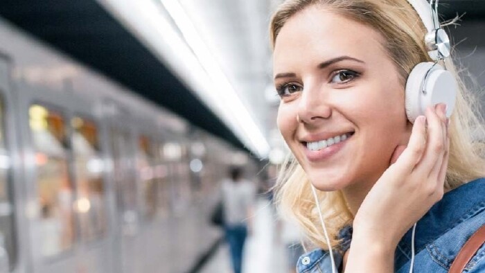 Pendlerin mit Headphones am Bahnhof