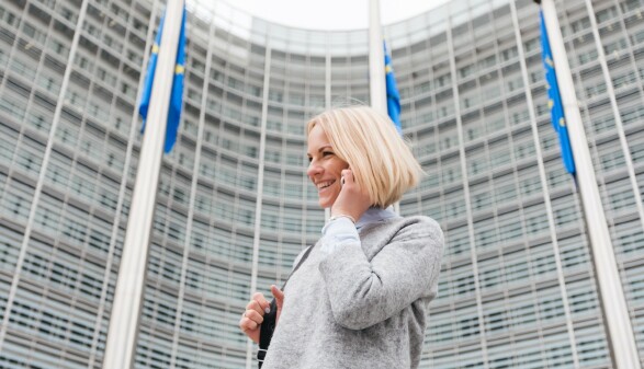 Eine junge Frau spaziert mit dem Handy in der Hand an der Europ&auml;ischen Kommission vorbei.