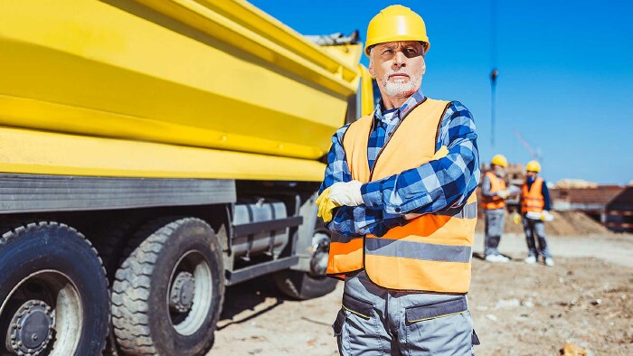 Bauarbeiter mit Helm steht vor einem Lastwagen