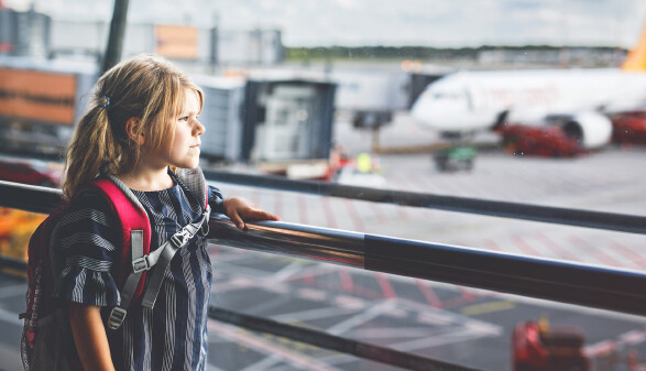 Little girl at the airport waiting for boarding at the big window. 