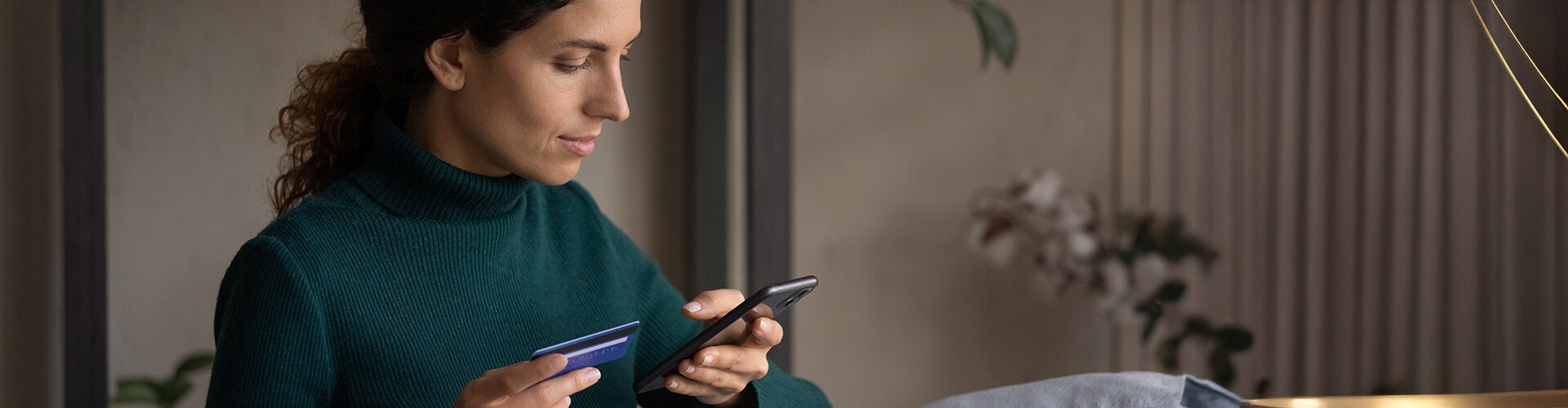 Eine fokussierte junge Frau führt eine bargeldlose Zahlung mit einer mobilen Bank-App durch.