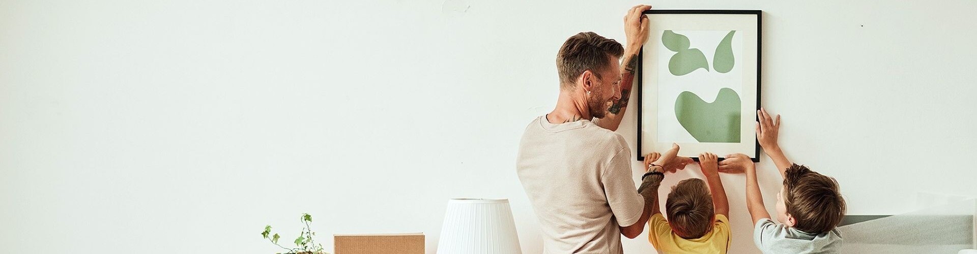 Papa und Söhne hängen ein Bild in der neuen Wohnung auf