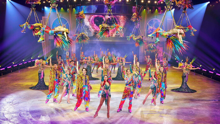 Ensemble von Holiday on Ice in bunten Kost&uuml;men in der Schlusspose auf dem Eis.