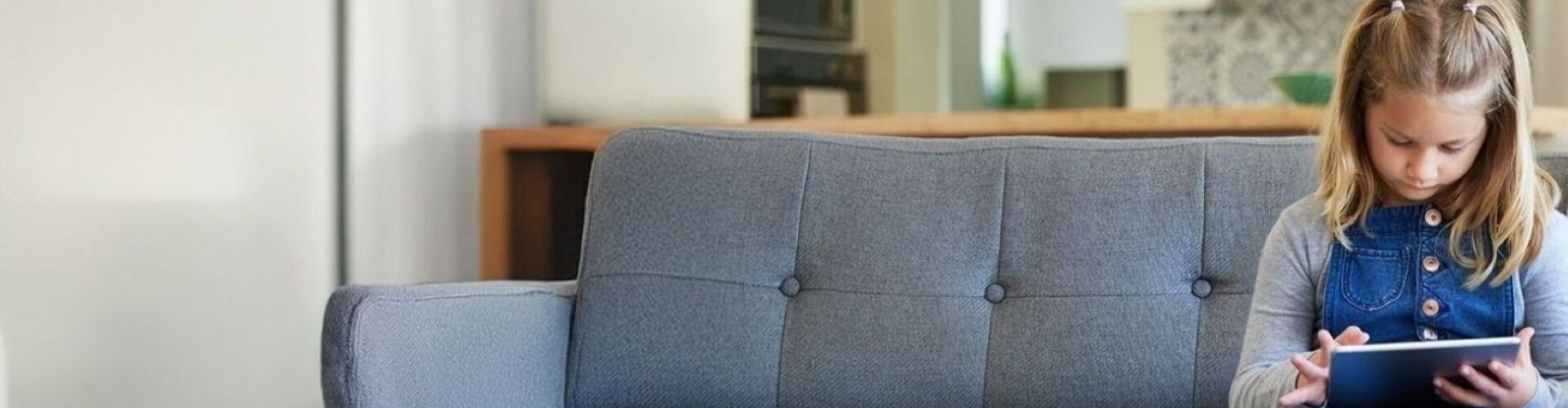 Mutter mit Laptop und Tochter mit Tablet sitzen auf dem Sofa im Wohnzimmer