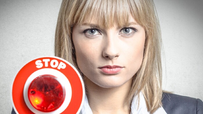 Junge Frau h&auml;lt ein Stopp Schild in der Hand.