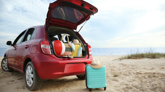 Knalloter Mietwagen parkt am Meer mit offenem Kofferraum