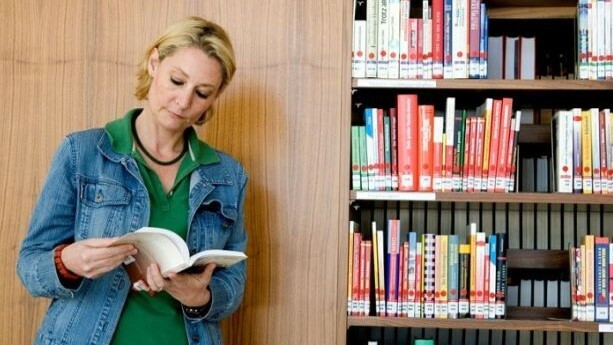 Junge Frau liest ein Buch in einer Bibliothek 