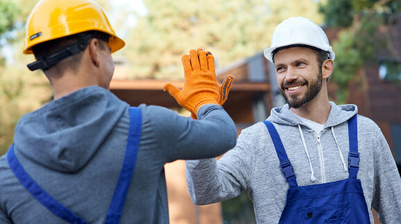 High five zweier junger Arbeiter auf der Baustelle